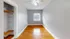 Bright bedroom with sleek hardwood floors, fresh gray walls, and a spacious open closet under a chic ceiling fan.