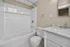 Elegant bathroom with a modern white bathtub, marble countertop sink, and stylish chrome fixtures.