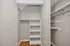 Spacious walk-in closet featuring built-in shelving and elegant hardwood flooring.