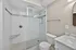Elegant bathroom featuring a sleek glass shower, classic subway tiles, and a stylish marble vanity.