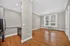 Bright and airy apartment interior featuring a modern kitchen with stainless steel appliances and a spacious open living area with hardwood flooring and large windows.