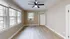 Bright room featuring large windows, a ceiling fan, and hardwood floors.