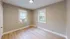 Spacious room with two windows and wooden flooring, featuring a neutral palette.