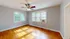 Sunlit corner room with hardwood floors and large windows featuring a ceiling fan and air conditioning unit.