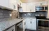 Contemporary kitchen featuring granite countertops, stainless steel appliances, and white cabinetry.
