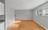 Spacious living area with wooden floors, large windows, and modern grey walls.
