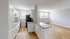 Modern open kitchen with white cabinetry, granite countertops, and adjoining bright living space with wood flooring.