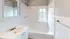Bright and elegant bathroom featuring a sleek sink, white cabinetry, and a classic tiled bathtub.