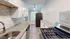 Chic kitchen with granite countertops, stainless steel appliances, and white cabinets with natural light flooding through large window.