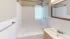 Bright contemporary bathroom with a bathtub, vanity, and a large mirror.