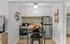 Modern compact kitchen with stainless steel appliances and a central dining nook.