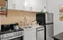 Modern small kitchen with stainless steel appliances, white cabinetry, and stylish backsplash.