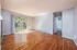 Spacious living room with hardwood floors, large windows, and a view of greenery.