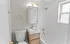 Modern bathroom featuring sleek gold fixtures, a white vanity, and a tiled shower area with a window for natural light.