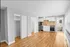 Bright and modern apartment with open-concept kitchen featuring white cabinets, sleek appliances, and natural wood flooring.