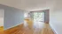 Bright and spacious living area featuring elegant hardwood floors, large sliding glass doors opening to a serene balcony, and a modern wall-mounted air conditioner.