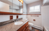 Bright and inviting bathroom featuring a granite countertop, large mirror, and natural light from a window, offering a serene atmosphere.