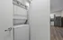 Modern apartment featuring an in-unit stacked washer and dryer adjacent to a sleek kitchen with stainless steel appliances and elegant wood flooring.