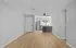 Modern apartment interior featuring open-concept layout with sleek laminate flooring, stainless steel refrigerator, and a stylish ceiling fan.