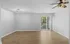 Bright and spacious living area with elegant wooden flooring, modern ceiling fan, and large sliding glass doors opening to a lush garden view.
