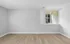 Bright, spacious room with sleek wooden flooring and a large window offering a serene view, perfect for customization.