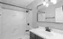 Elegant bathroom featuring modern black fixtures, a sleek vanity, and a marble-patterned shower wall.