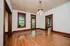 Charming room with gleaming hardwood floors, vintage wooden trim, and natural light through expansive windows and glass doors.