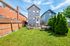 Charming suburban backyard featuring a cozy patio area with seating, surrounded by lush greenery and a wooden fence.