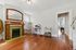 Charming living space with polished wooden floors, a cozy green-tiled fireplace, and a modern workspace.
