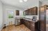 Charming kitchen with rich wooden cabinets, modern appliances, and natural light through the window and door.