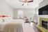 Bright and airy bedroom with elegant decor, featuring a cozy bed, stylish desk, and a charming fireplace with a green tile surround.