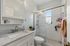 Bright and modern bathroom featuring a marble countertop, sleek white cabinetry, and a spacious glass-enclosed shower.