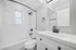 Elegant bathroom with modern fixtures, featuring a pristine white bathtub, stylish black faucet, and large mirror creating a fresh and inviting space.