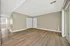 Spacious living area with elegant wood flooring and neutral walls, featuring ample natural light from large windows and modern finishes.