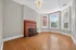 Charming living room with elegant hardwood floors, a classic red brick fireplace, and expansive windows welcoming natural light.