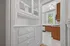 Charming kitchen view with classic white cabinetry and modern wood accents, brightened by natural light through large windows.