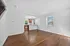 Bright and inviting living area with rich hardwood floors, open kitchen layout, and ample natural light from large windows.