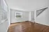 Bright and airy living room with hardwood floors, large windows, and a modern staircase, ideal for comfortable living.