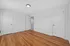 Bright and spacious room with elegant wooden flooring, featuring white doors and smooth white walls, ideal for cozy living.