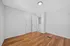 Bright room with wooden floors, white walls, and closed white closet doors.