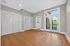 Bright and inviting room with wooden flooring, large storage closet, and glass doors leading to a charming balcony with nature views.