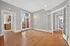Charming living space with hardwood floors and French doors, leading to a bright kitchen and cozy balcony view.