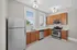 Bright modern kitchen with stainless steel appliances, cherry wood cabinets, and elegant tile flooring.