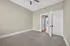 Bright and inviting bedroom with soft carpet, contemporary ceiling fan, and open doorway leading to sunlit hallway.