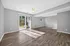 Bright and spacious living area with sleek hardwood floors, large sliding glass doors leading to a lush garden, and a modern ceiling fan.