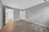 Bright, spacious bedroom with sleek wood flooring, gray walls, and multiple white doors leading to closets.