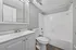 Modern white bathroom with elegant vanity, mirrored cabinet, and classic tub-shower combination.
