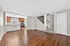 Inviting open-concept living area with sleek hardwood floors, modern kitchen with stainless steel appliances, and elegant staircase.