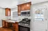 Cozy kitchen with rich wooden cabinets, sleek granite countertops, and modern stainless steel appliances, perfectly lit by natural light through a winter scene window.