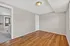 Bright room with elegant hardwood flooring and soft neutral walls, connecting to a cozy carpeted area with natural light.